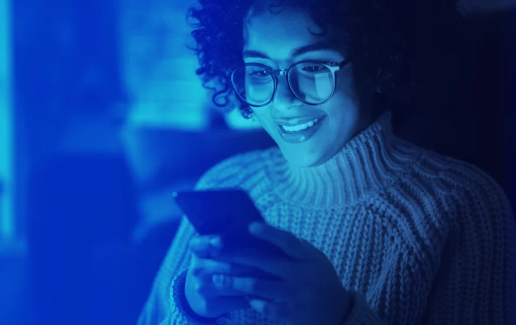 Smiling woman in glasses using a smartphone, representing customer satisfaction and seamless digital experience
