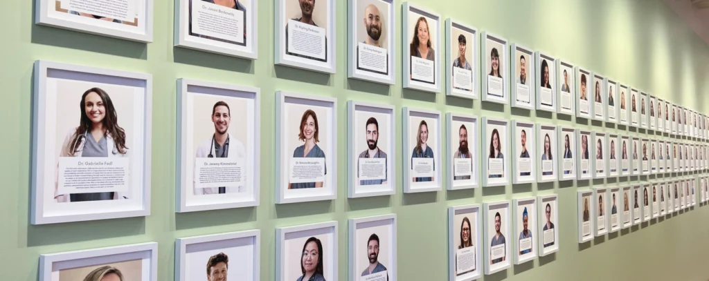 Framed portraits of BondVet team members displayed on a green wall, each with nameplates and bios showcasing the veterinary clinic’s people-first culture and commitment to care.